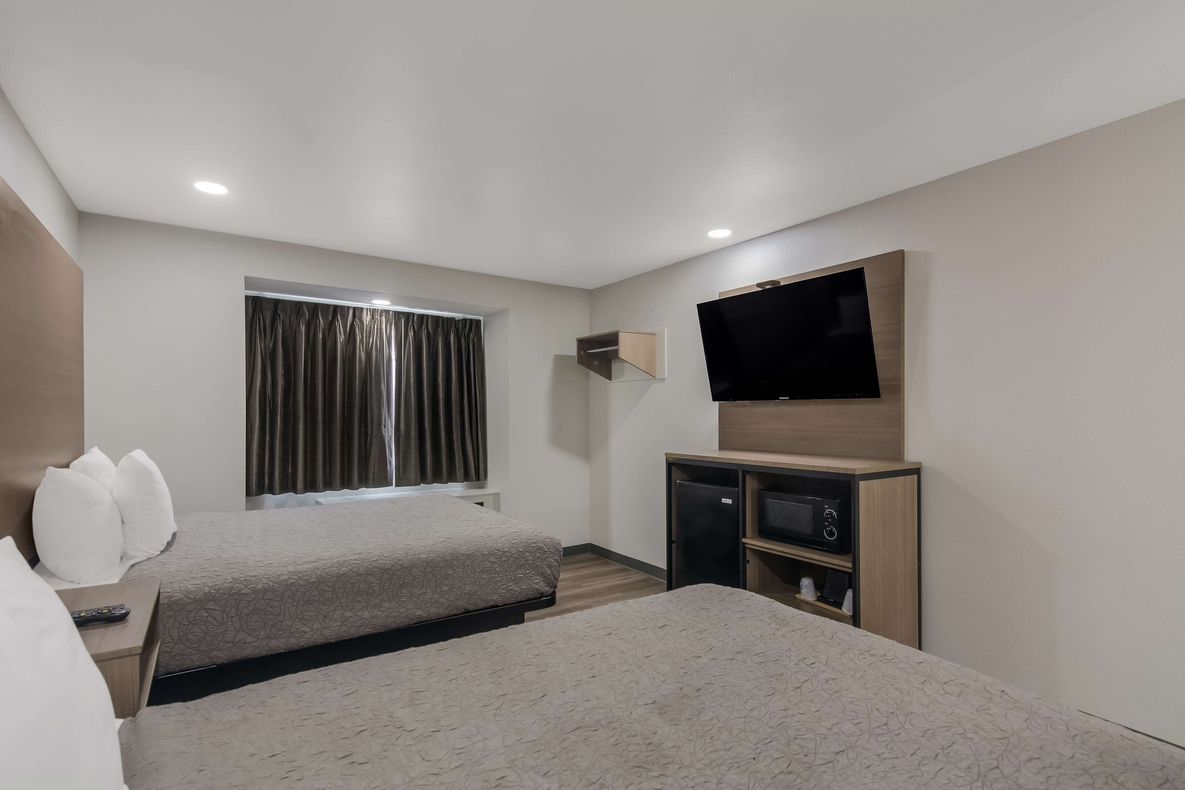 Ein Hotelzimmer mit zwei Betten, einem Flachbildfernseher, einer kleinen TV und einer Minibar.