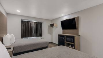 Ein Hotelzimmer mit zwei Betten, einem Flachbildfernseher, einer kleinen TV und einer Minibar.