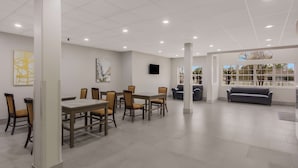 Un espace intérieur spacieux comprenant une table et des chaises, un canapé et une grande fenêtre offrant une belle vue.
