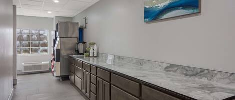 A modern kitchen with a marble countertop, built-in cabinets, and a stainless steel refrigerator.