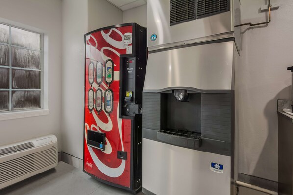 Una máquina expendedora con el logotipo de Coca-Cola, un dispensador de agua y un refrigerador de acero inoxidable.