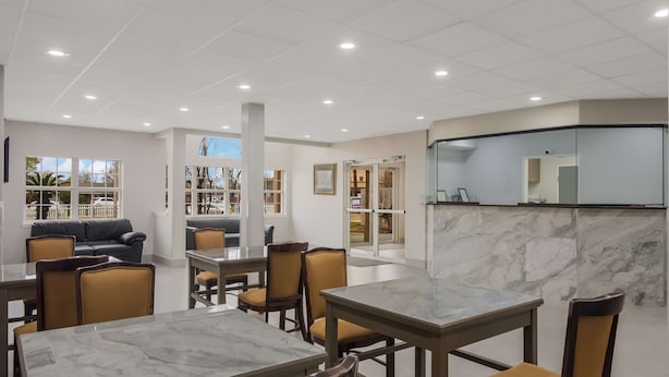 Un hall d’hôtel moderne avec des tables et des chaises surmontées de marbre, un canapé et une cloison en verre.
