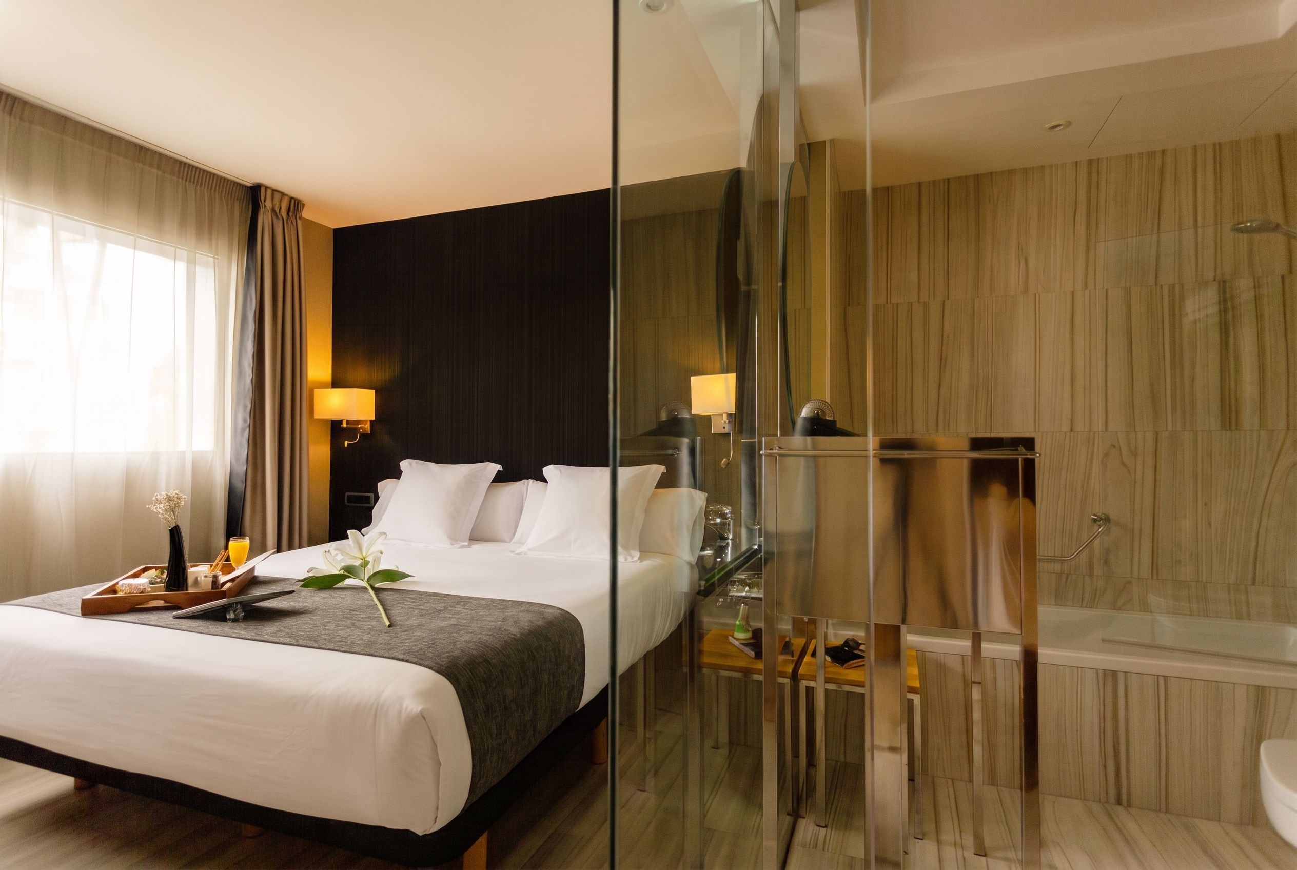 Ein Hotelzimmer mit Bett, Nachttisch, Lampe und einer Duschkabine.