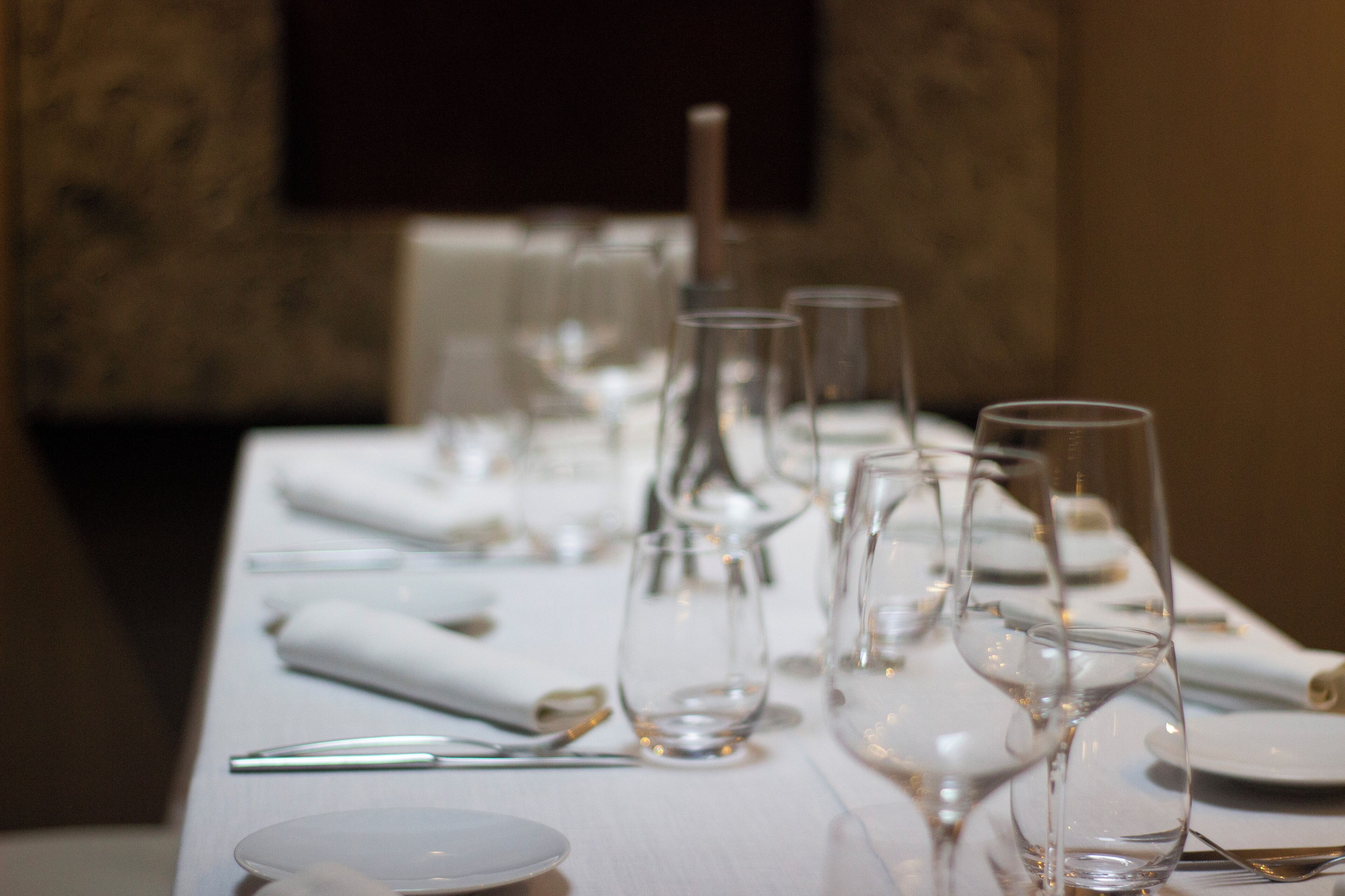 A table set with clear glassware and plates, indicating a formal dining arrangement.