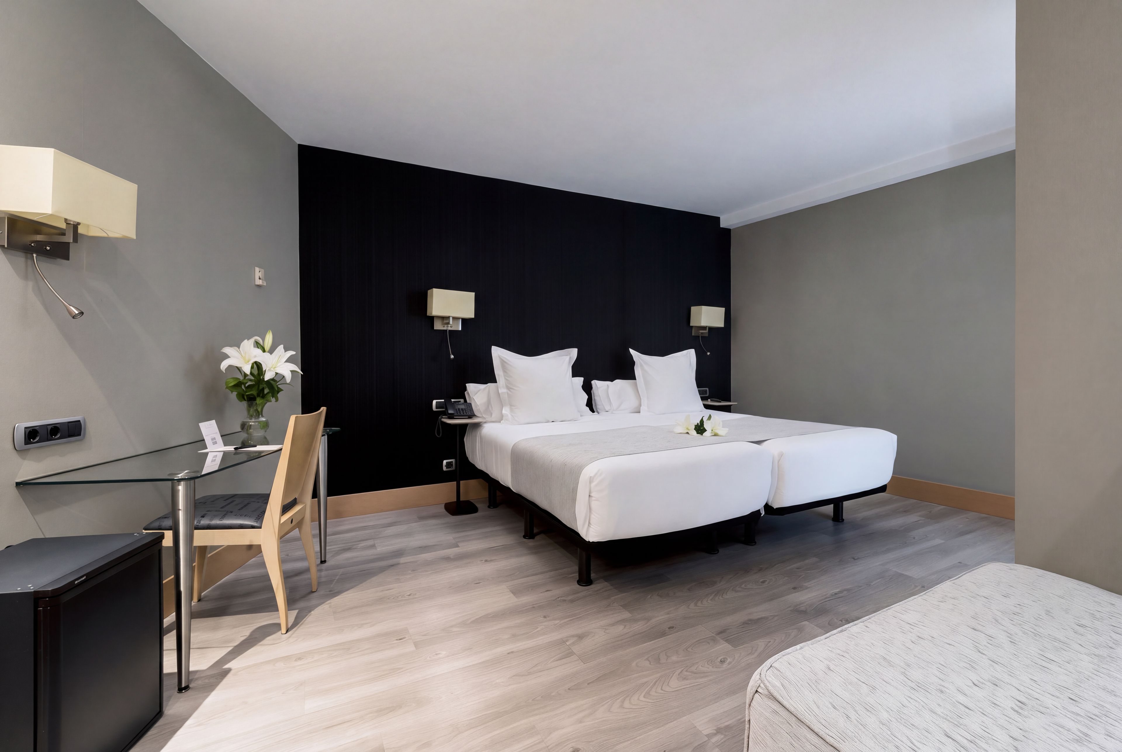 Une chambre d’hôtel moderne équipée d’un lit, de tables de chevet, d’un bureau et d’une chaise.