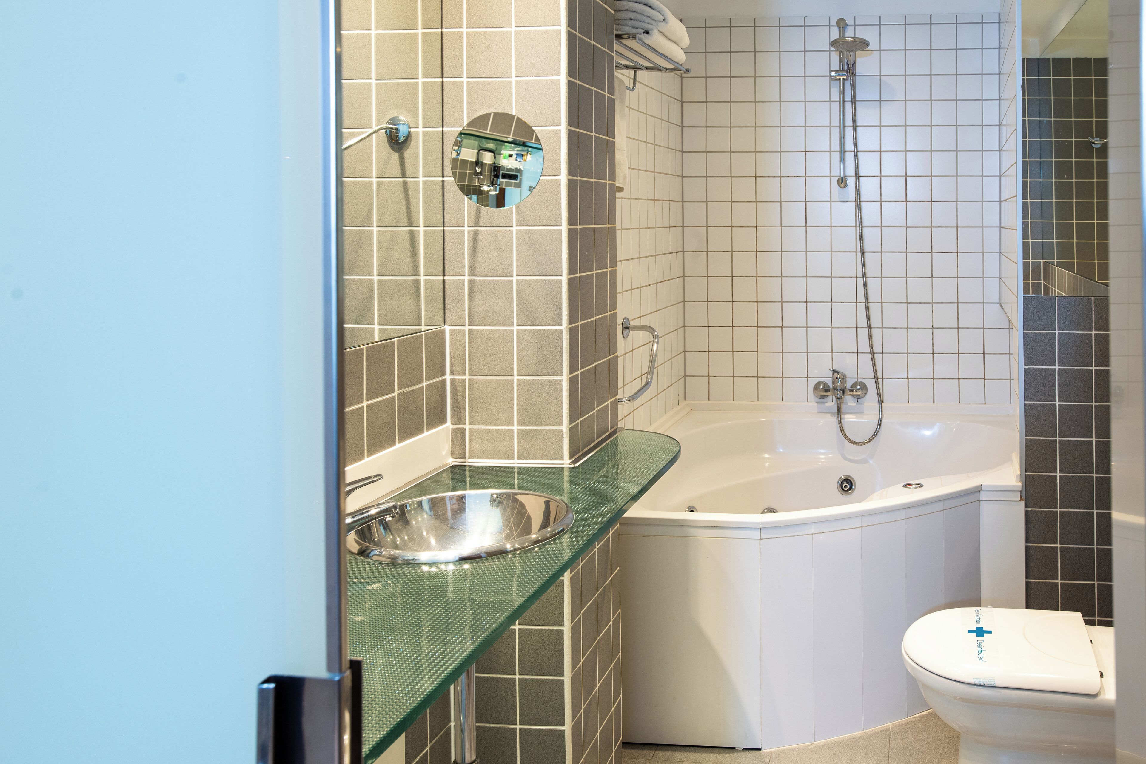 Un baño con lavamanos de vidrio, bañera y retrete.