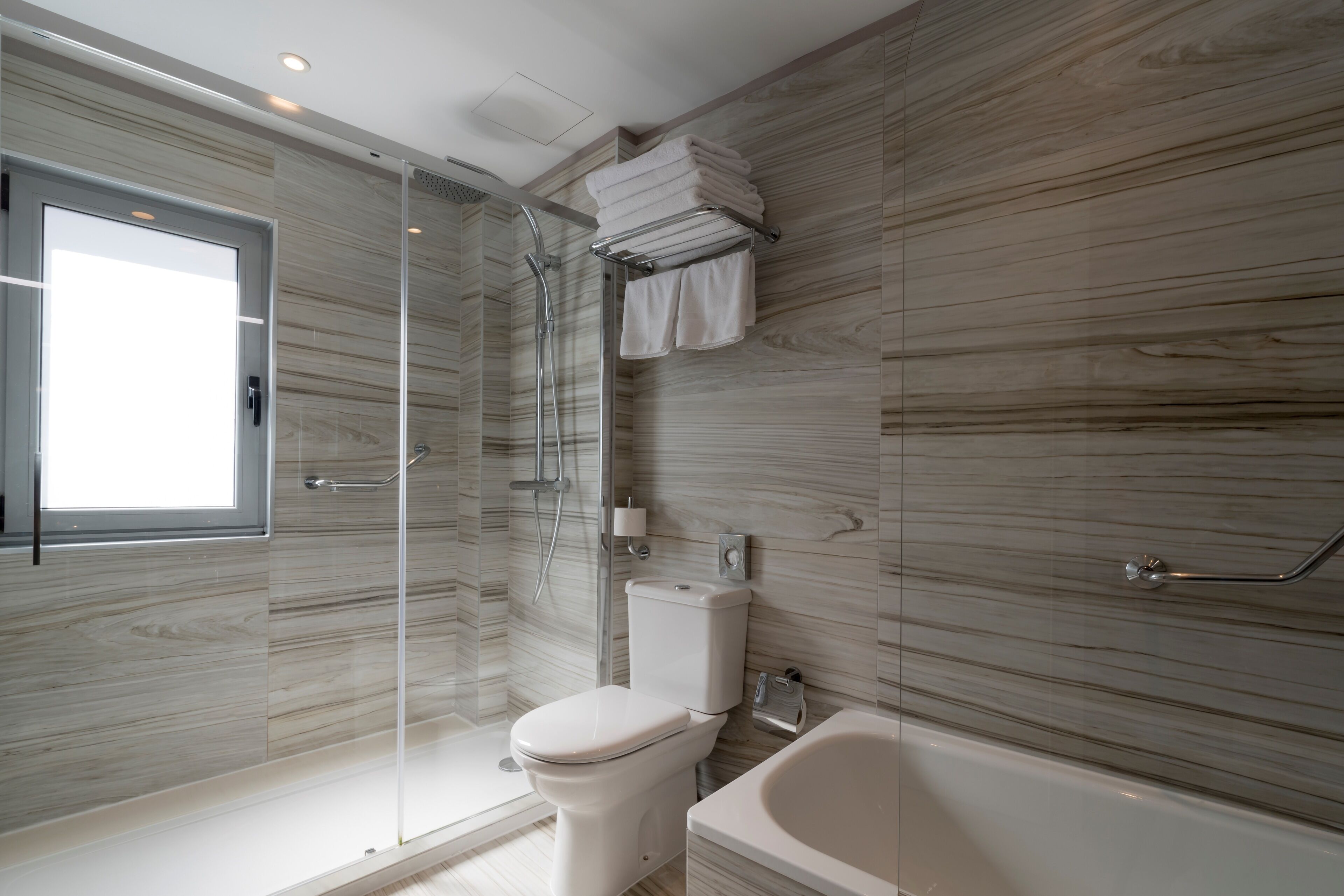 Un baño moderno con ducha envuelta en vidrio, inodoro y bañera.