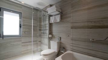 Un baño moderno con ducha envuelta en vidrio, inodoro y bañera.