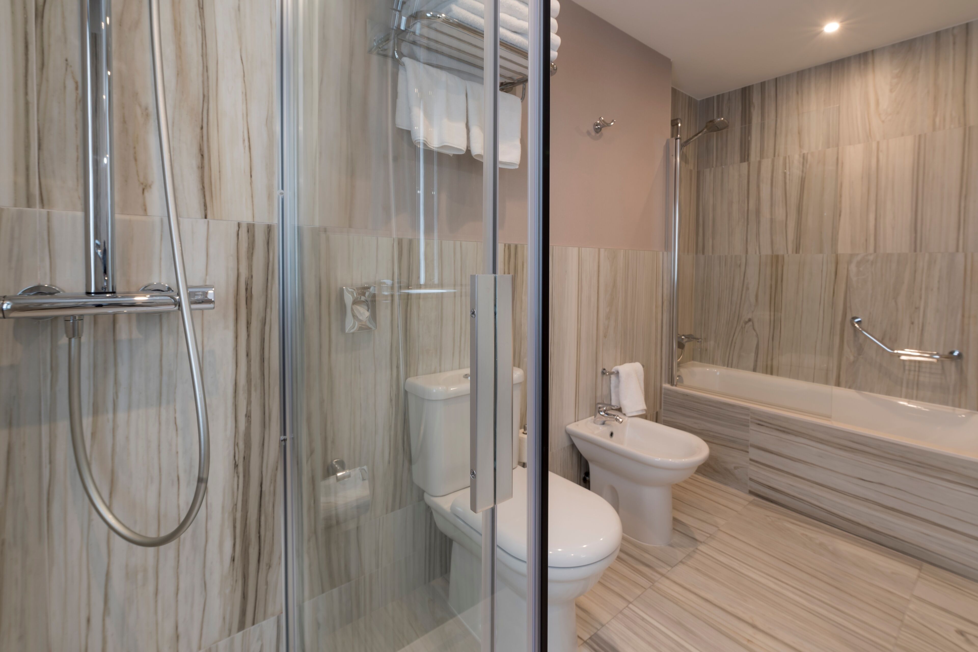 Un baño moderno con ducha de vidrio, inodoro, bidé y bañera.