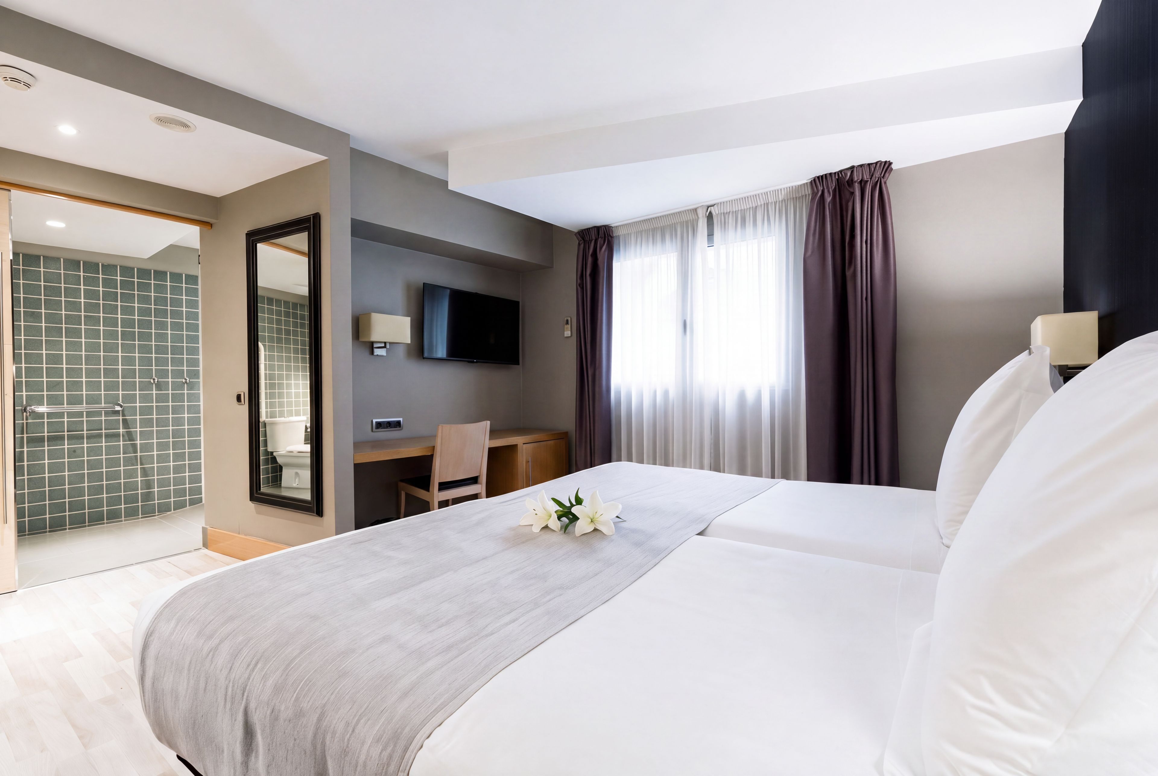 Ein Hotelzimmer mit einem Bett, einem Schreibtisch, einem Fernseher und einem Badezimmer.