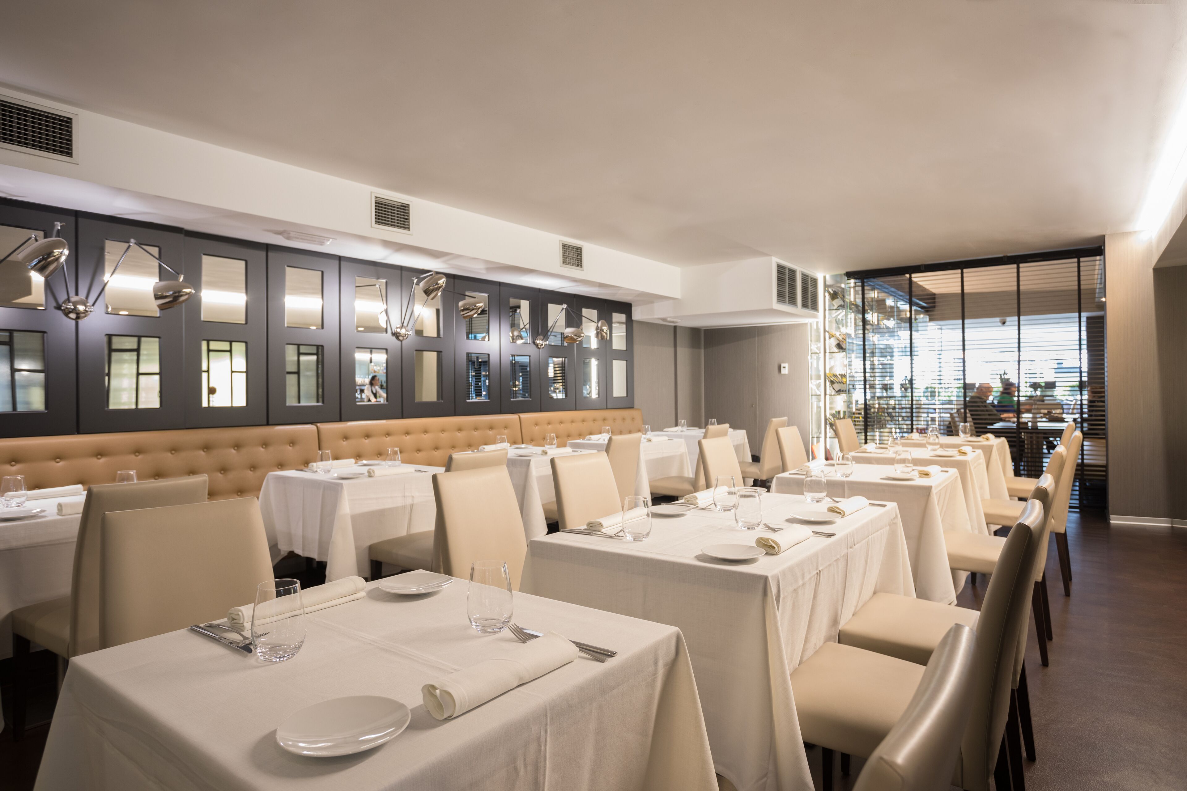 Ein Restaurant mit mehreren Tischen, jeweils mit weißer Tischdecke und Besteck gedeckt.