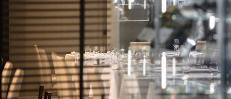 Comedor con mesas dispuestas para comer, sillas y un divisor de vidrio reflectante.