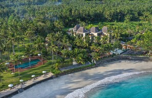 Vista aérea de un resort con varias construcciones, una piscina y acceso a la playa.