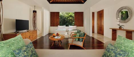 Una sala de estar moderna con televisor, sofá, mesa de centro y cojines decorativos.