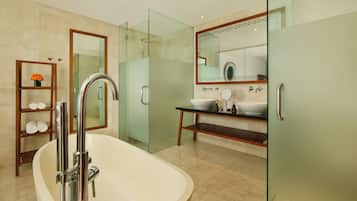 Un baño moderno con una bañera independiente, ducha con mampara de vidrio y tocador con un espejo grande.