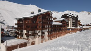 A multi-story wooden building with balconies, set against a snowy mountain backdrop. - Résidence le Rond Point des Pistes (Tignes)