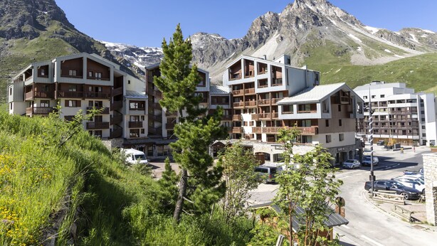 A multi-story hotel with balconies, set against a mountainous backdrop. - Odalys Residence le hameau du Borsat (Tignes)