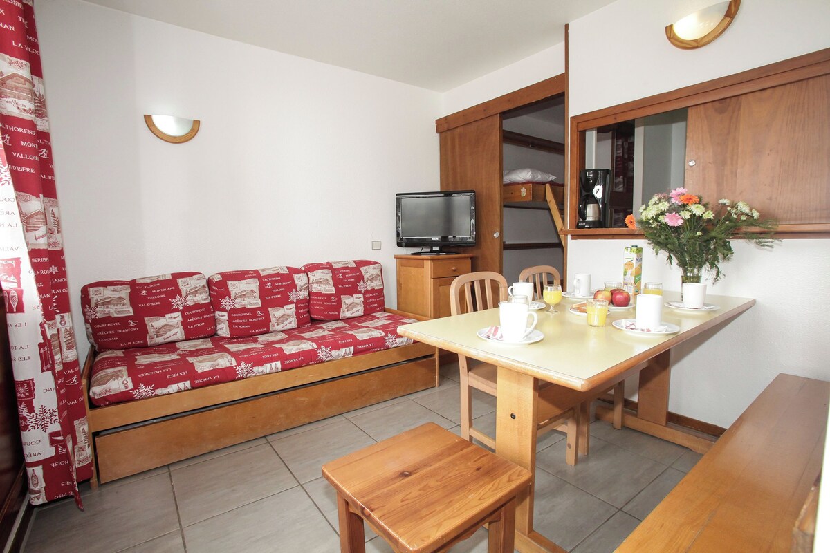 Un espace de vie compact comprenant un canapé, une table à manger avec des chaises, un téléviseur et un meuble.