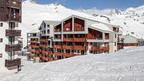 A multi-story hotel with balconies, set against a snowy mountain backdrop. - Odalys Residence le hameau du Borsat (Tignes)
