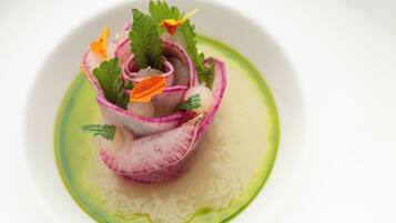 A white plate with a pink and white flower arrangement and green sauce.