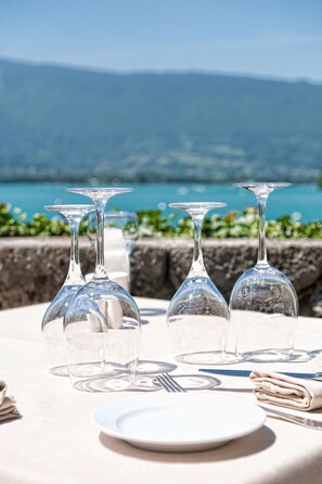 Una mesa con copas de vino, un plato y cubiertos, con vistas a un paisaje idílico.