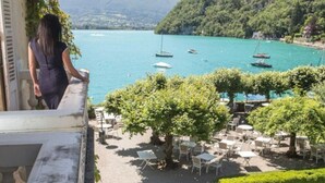 Terraza con mesas al aire libre y vista a un lago con barcos.