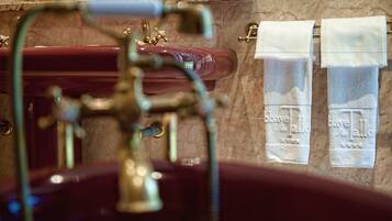 A bathroom with a marble sink, a gold faucet, and two towels hanging on a towel rack.