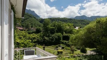 A balcony with a view of a lush garden and mountains.