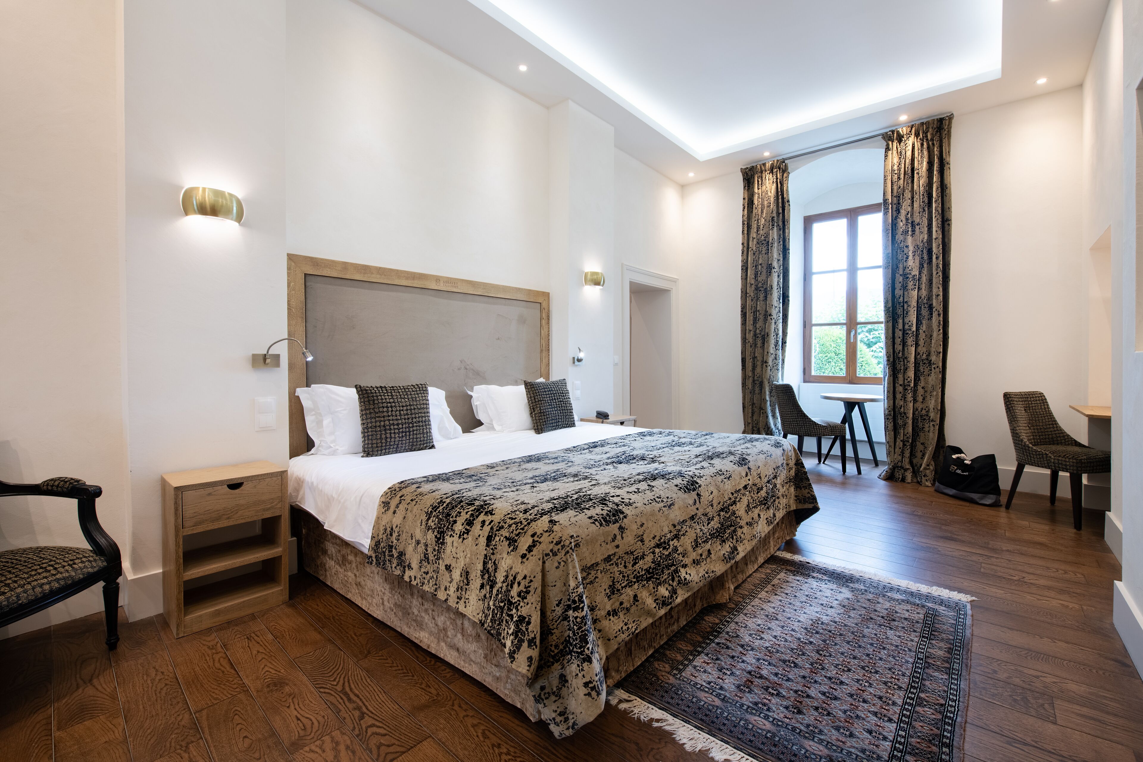 A modern bedroom with a large bed, bedside tables, a desk, and a chair.