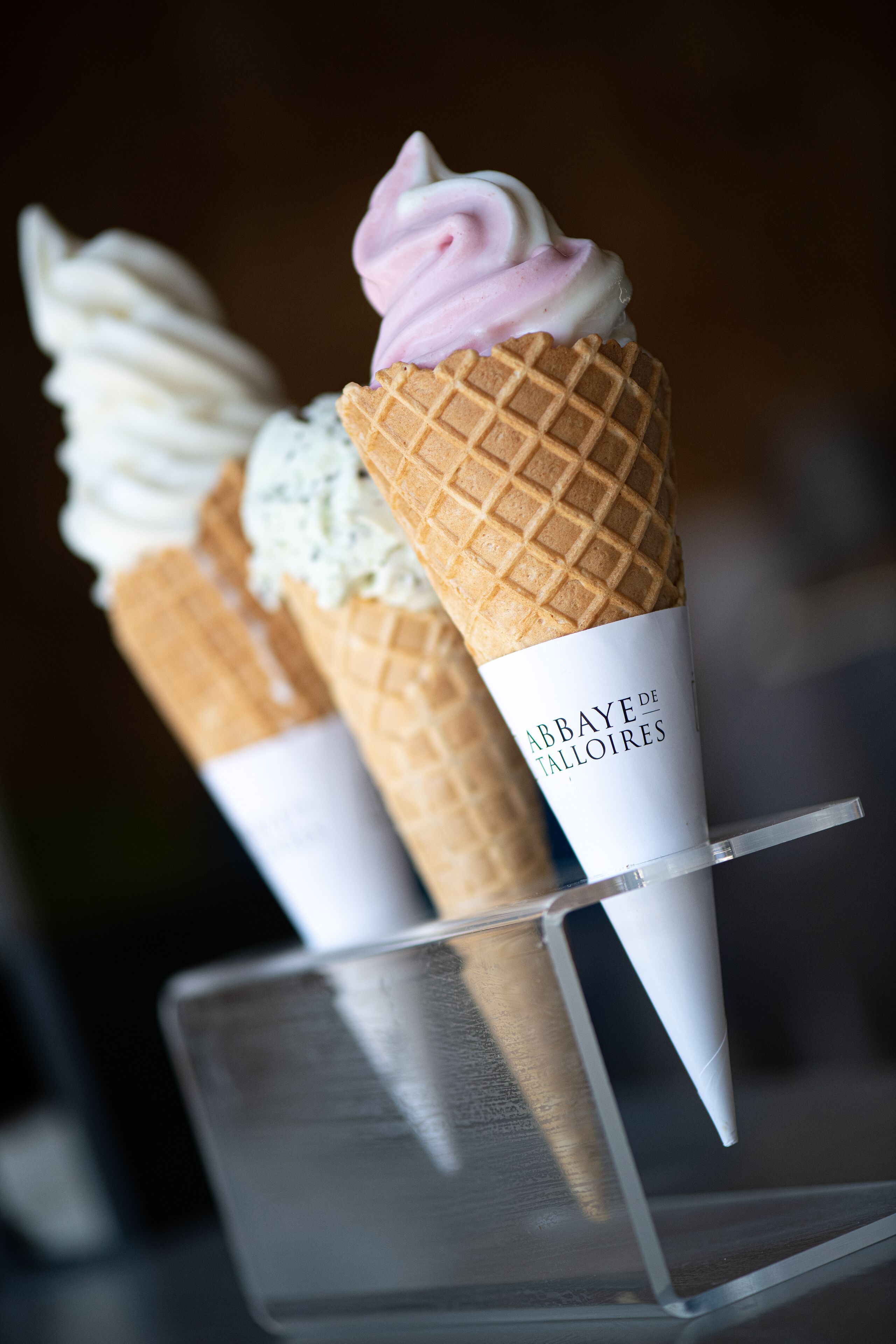 Tres helados de diferentes sabores sobre un expositor transparente.