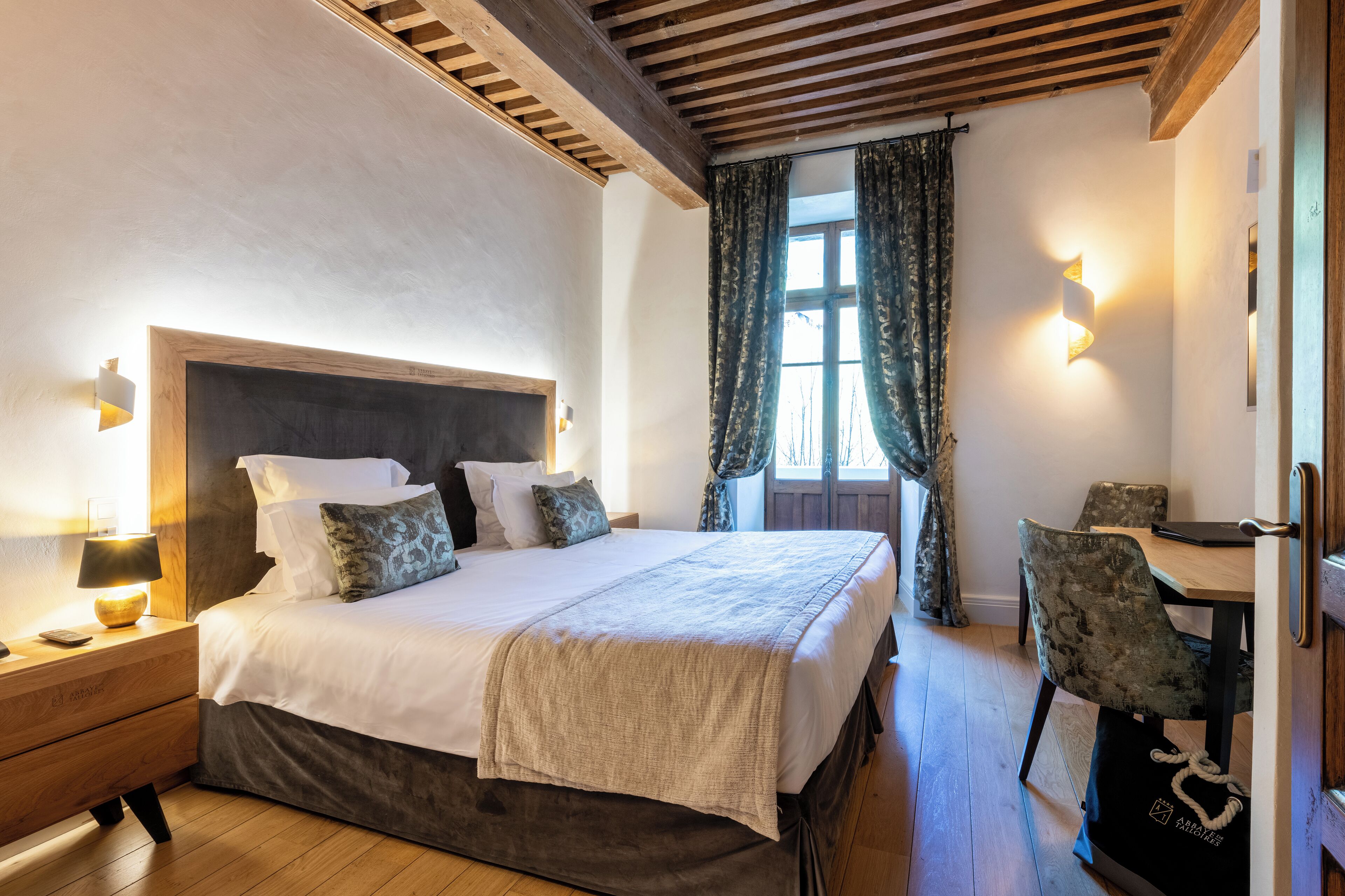 Un dormitorio ordenado con una cama grande, mesitas de noche, un escritorio y una silla.