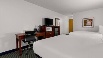 Una habitación de hotel con cama, escritorio con computadora, televisión, microondas y refrigerador.