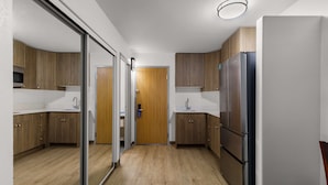 Una cocina moderna con armarios de madera, un refrigerador de acero inoxidable y una puerta de vidrio que da a otra habitación.