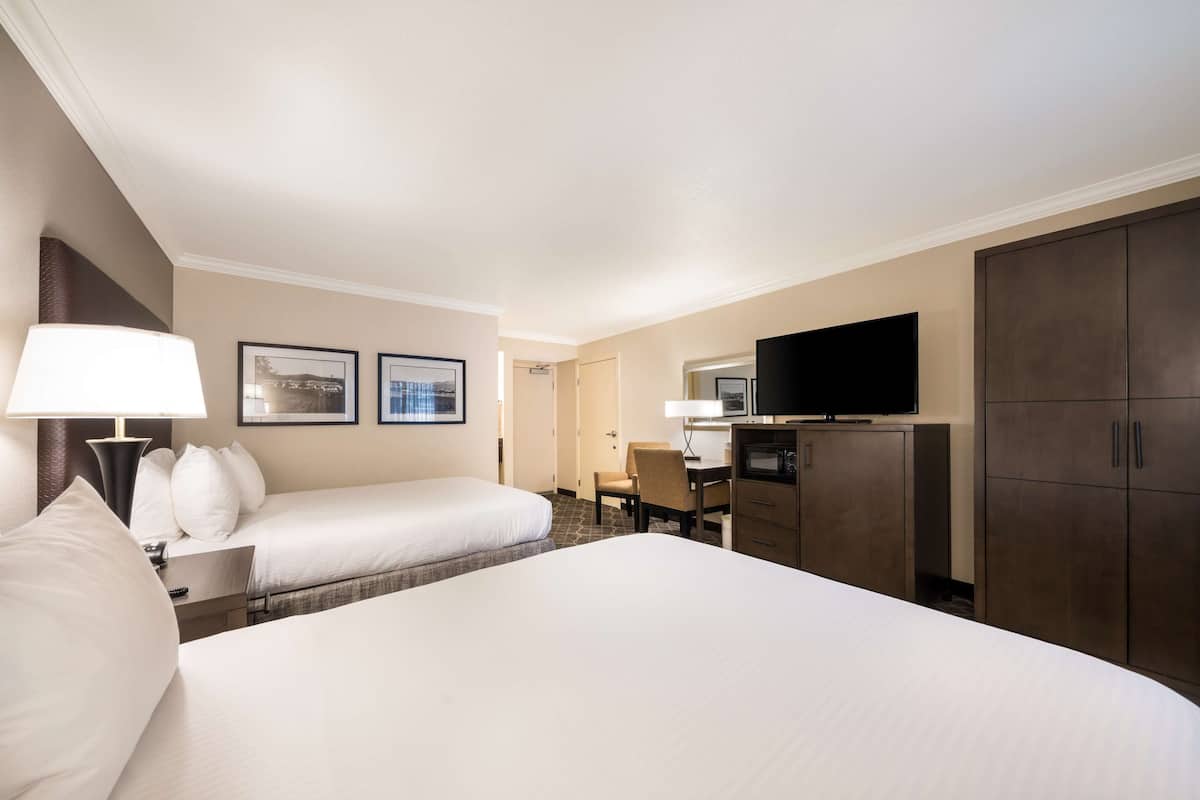 A hotel room with two beds, a desk, a television, and a wardrobe.