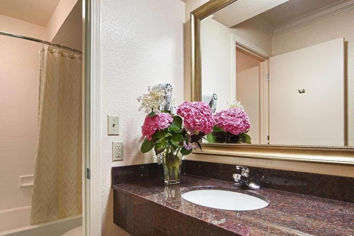 A bathroom with a marble sink, a mirror, and a shower curtain.