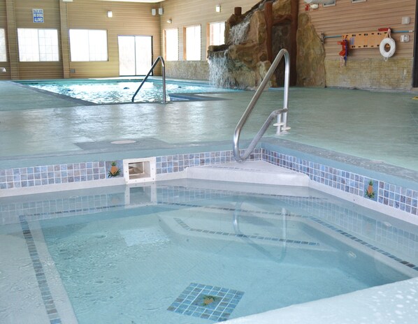 Una piscina interior con un trampolín, una estación de socorristas y un flotador en la pared.