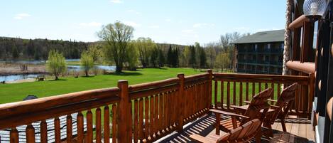 Terraza de madera con mobiliario exterior con vistas a un lago y un campo de golf.
