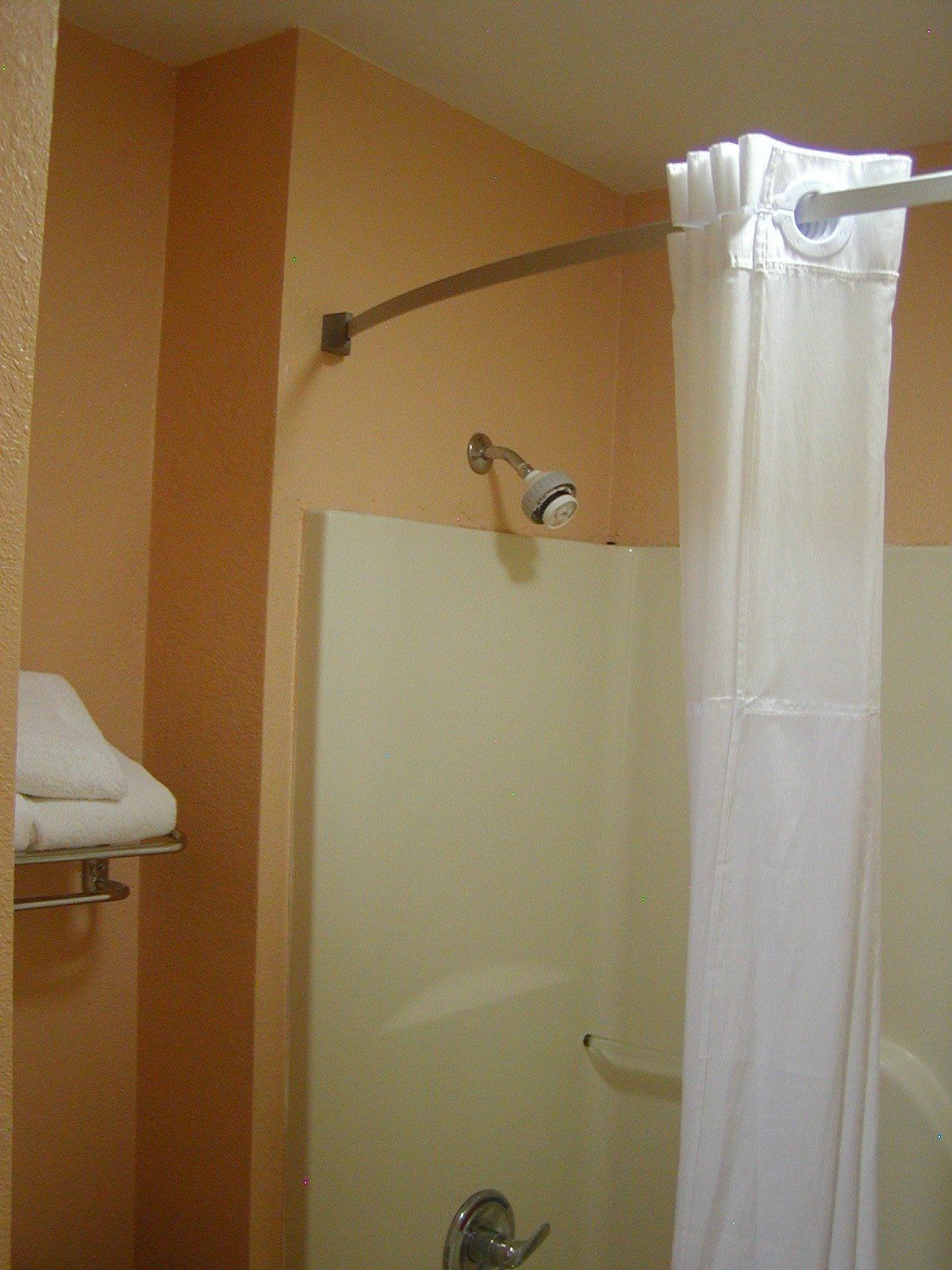 A bathroom with a shower curtain, a towel rack, and a showerhead.