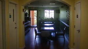 A hallway with a dining area featuring a table and chairs, a staircase, and a door with an exit sign. - Days Inn by Wyndham Marietta White Water (Marietta)