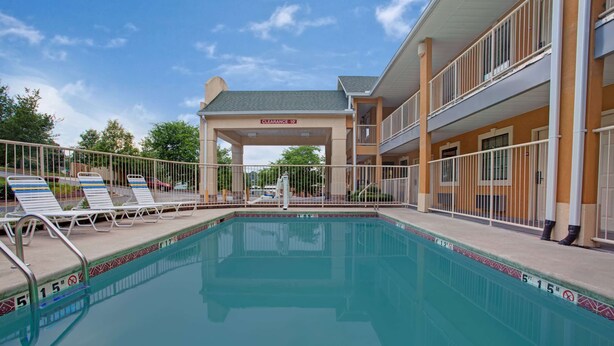 A swimming pool with lounge chairs and a covered area with a sign indicating 'Clearance 10'. - Days Inn by Wyndham Marietta White Water (Marietta)
