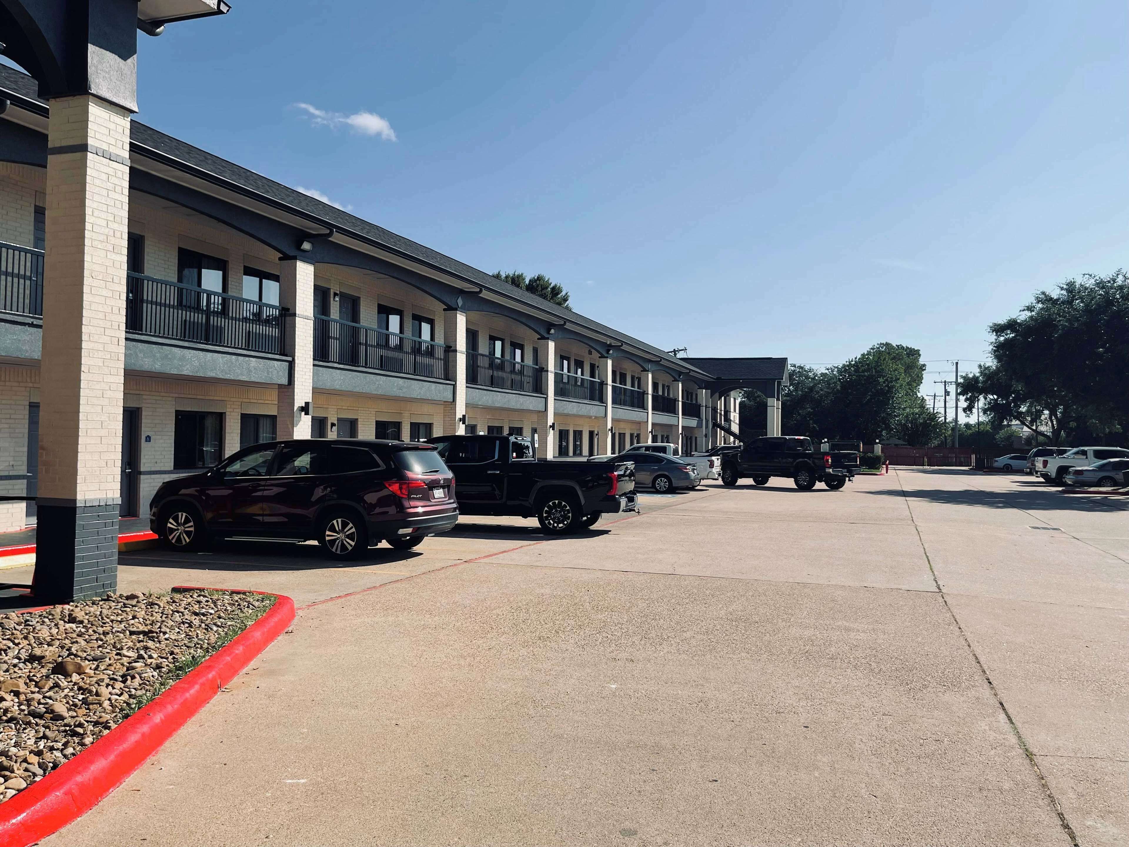 Ein Motel mit mehreren Etagen, Außenparkplatz und einem überdachten Gang.