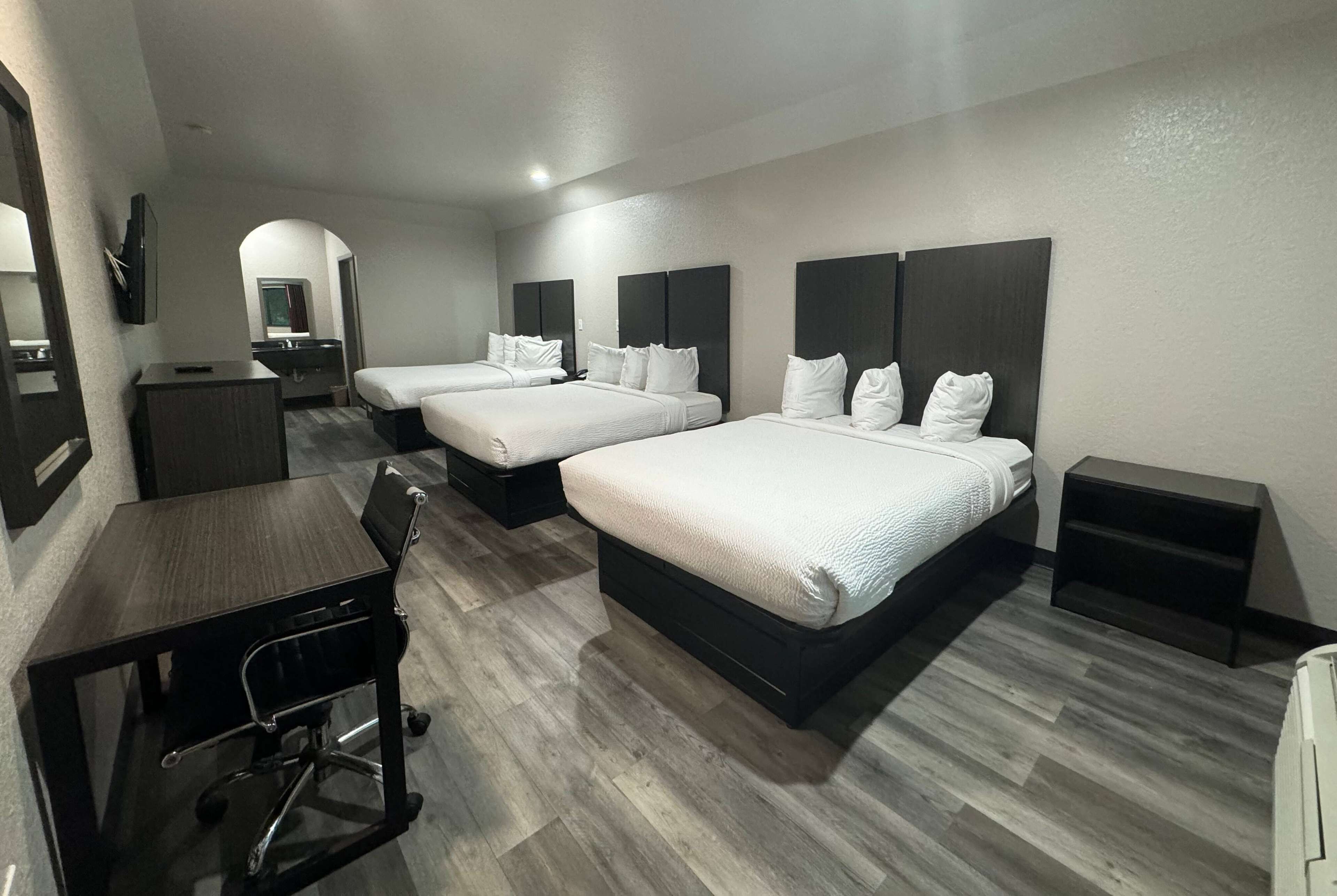 Una habitación de hotel con dos camas, un escritorio, una silla y un televisor.
