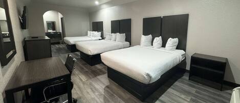 Una habitación de hotel con dos camas, un escritorio, una silla y un televisor.