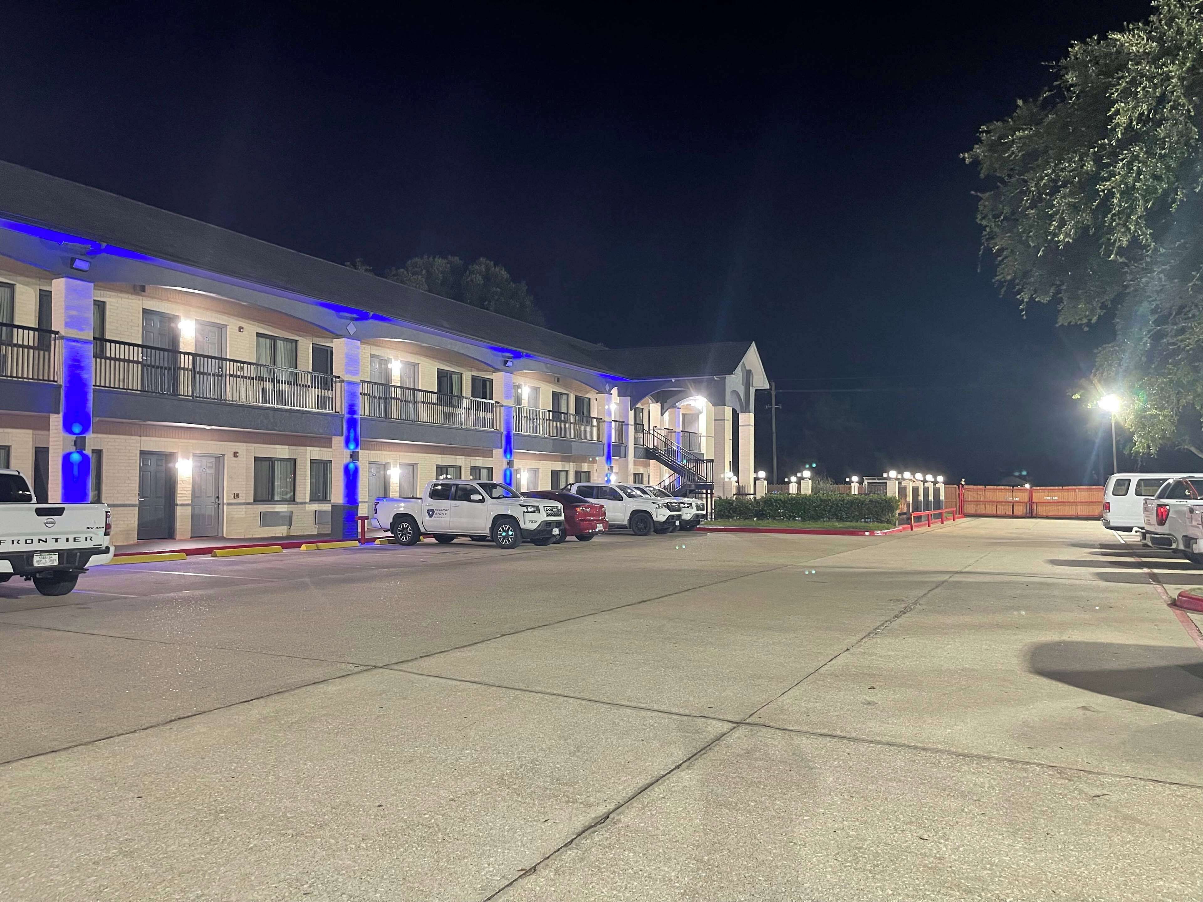 Un motel con varios pisos, un estacionamiento y varios vehículos aparcados.