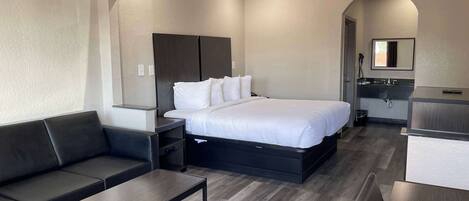Et moderne hotelværelse med seng, sofa, skrivebord og badeværelse.