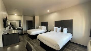 A hotel room with two beds, a desk, and a mirror.