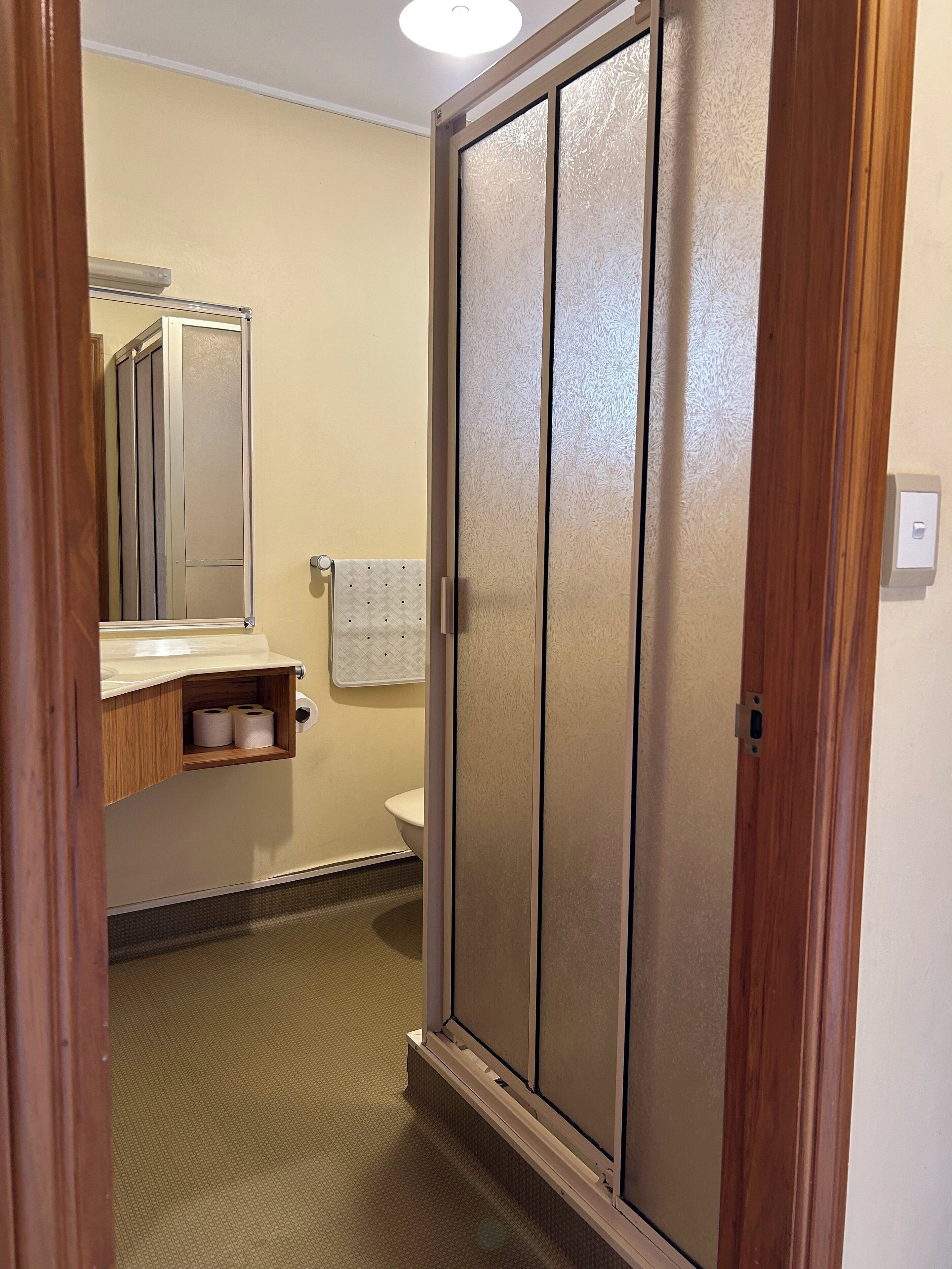 Un bagno con un WC, uno specchio e un mobiletto con carta igienica.