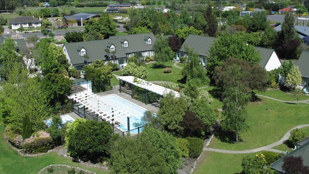A residential area with houses, a swimming pool, and a well-maintained lawn.