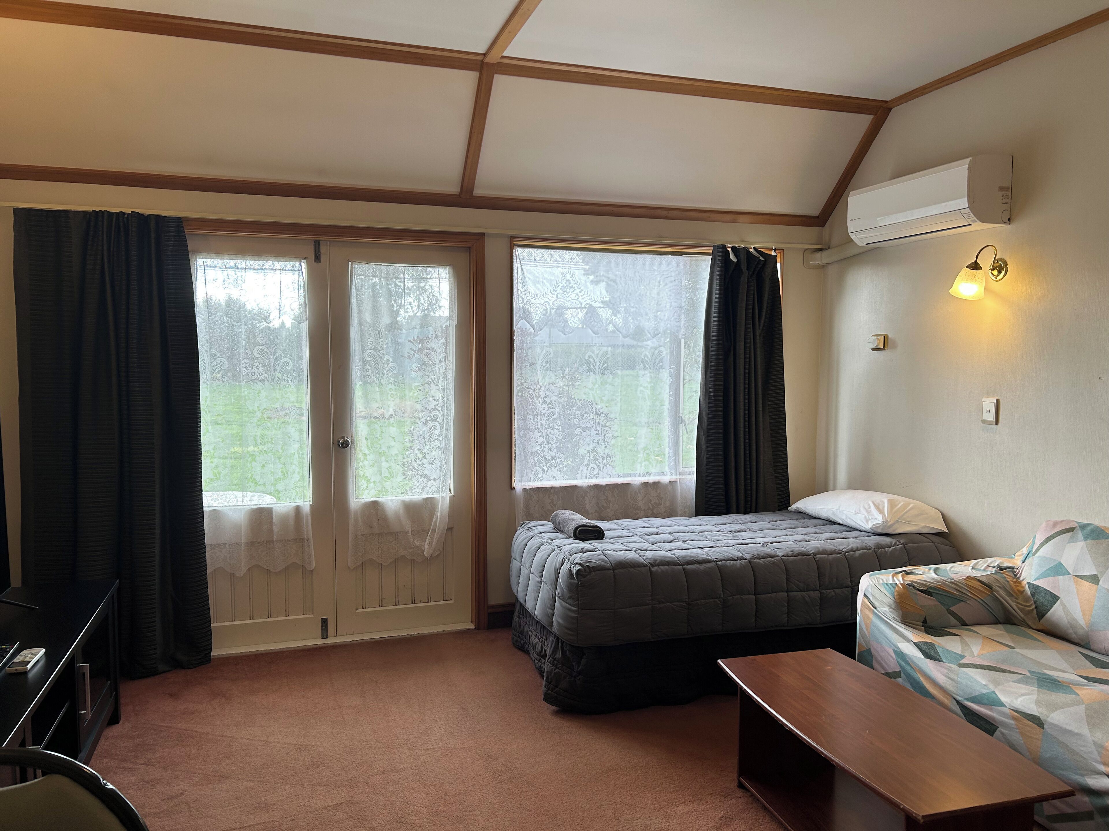 Una habitación con cama, sofá, escritorio y ventana con cortinas.