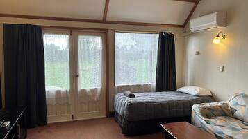 Una habitación con cama, sofá, escritorio y ventana con cortinas.